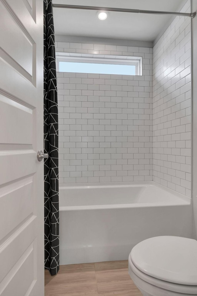 full bathroom with toilet, shower / bath combo with shower curtain, and wood finished floors