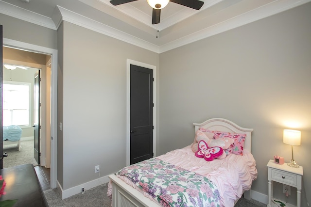 bedroom with baseboards, a ceiling fan, a tray ceiling, crown molding, and carpet floors