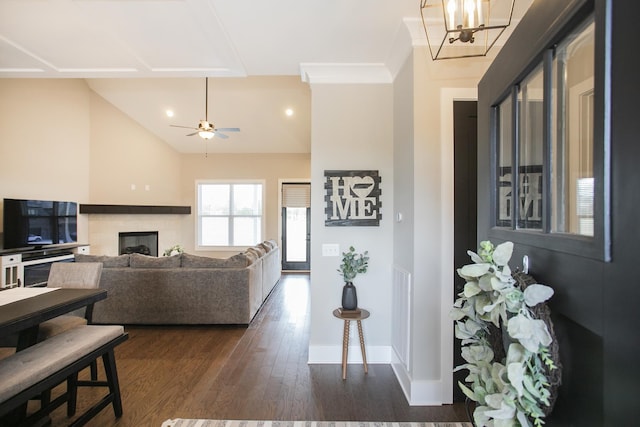 living area featuring lofted ceiling, ceiling fan with notable chandelier, a fireplace, baseboards, and dark wood-style floors