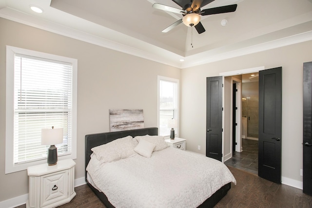 bedroom with dark wood-style floors, a tray ceiling, ornamental molding, and baseboards