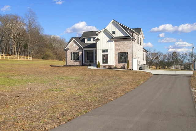 modern farmhouse style home with brick siding, board and batten siding, a garage, driveway, and a front lawn