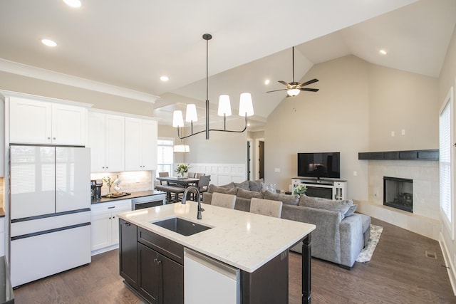 kitchen featuring dark wood-style floors, freestanding refrigerator, white cabinetry, a sink, and a tile fireplace