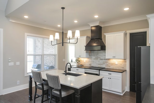 kitchen featuring crown molding, custom range hood, backsplash, freestanding refrigerator, and a sink