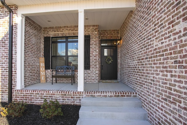 property entrance with a porch and brick siding