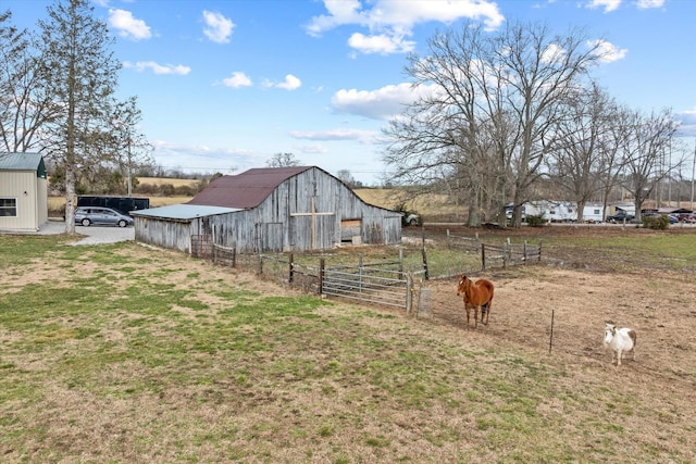 view of yard with an outbuilding, a rural view, a barn, and fence