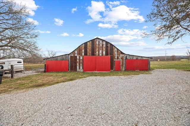 view of barn with fence and a yard