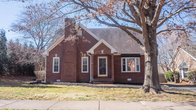 view of front of home featuring brick siding, roof with shingles, a chimney, a front yard, and crawl space