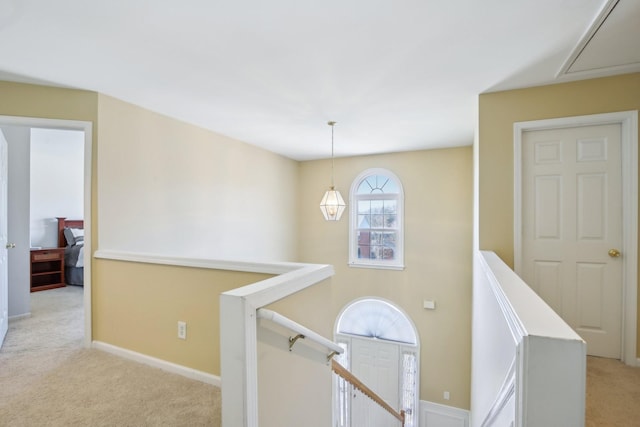 corridor featuring baseboards, light colored carpet, and an upstairs landing