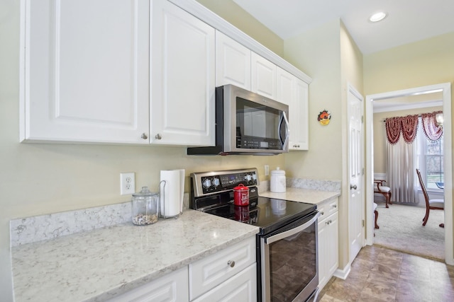 kitchen featuring recessed lighting, light colored carpet, appliances with stainless steel finishes, white cabinetry, and light stone countertops