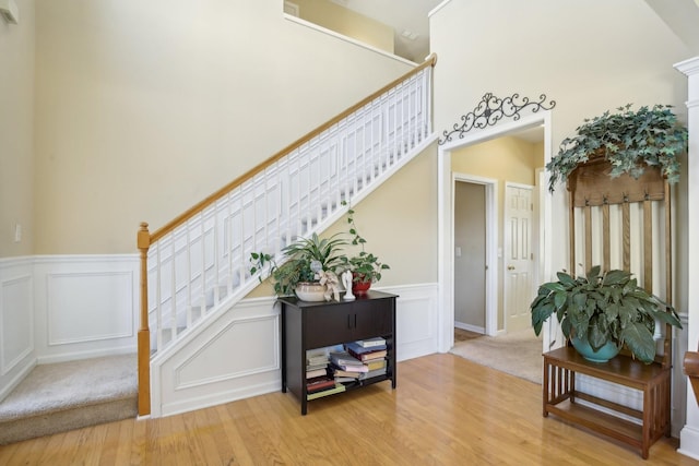 stairway featuring wainscoting, wood finished floors, and a decorative wall