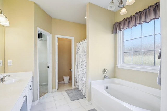 bathroom with tile patterned flooring, vanity, baseboards, and a bath