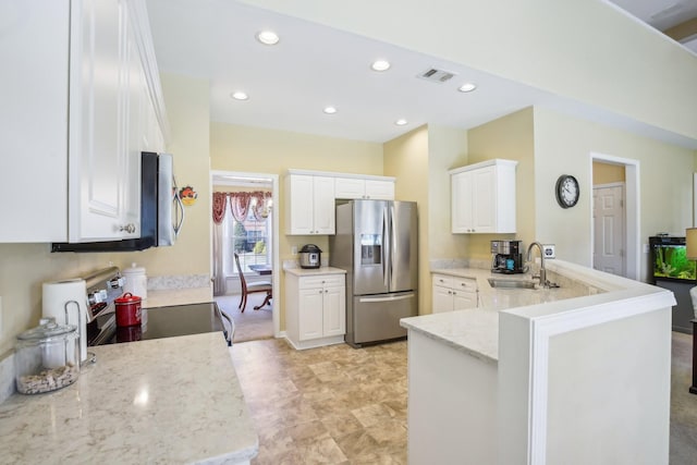 kitchen featuring a peninsula, appliances with stainless steel finishes, a sink, and white cabinetry