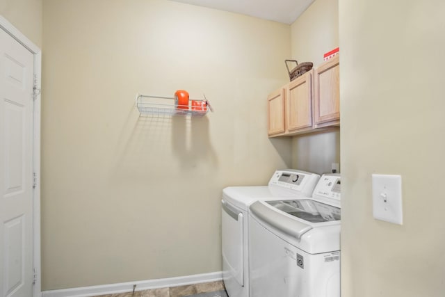 clothes washing area featuring washing machine and dryer, cabinet space, and baseboards