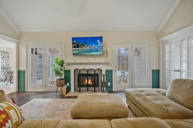 interior space featuring a fireplace with flush hearth, lofted ceiling, ornamental molding, and wood finished floors