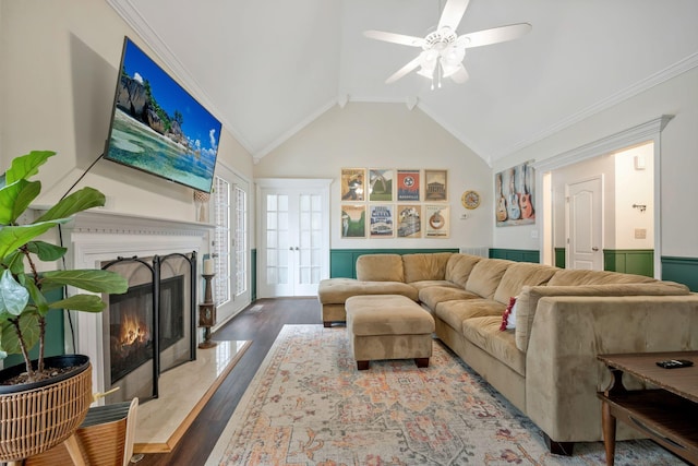 living room featuring a wainscoted wall, a premium fireplace, wood finished floors, vaulted ceiling, and ornamental molding