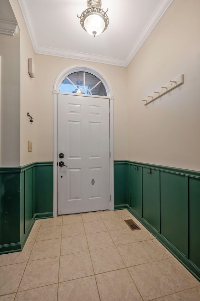 foyer entrance with a wainscoted wall, light tile patterned floors, visible vents, and crown molding