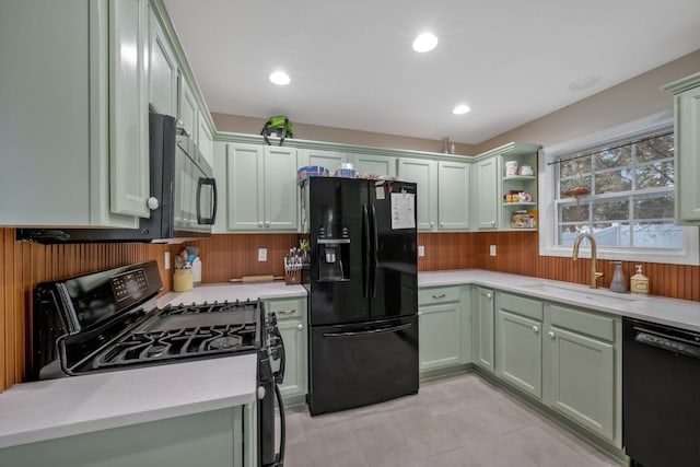 kitchen with green cabinets, light countertops, black appliances, open shelves, and a sink