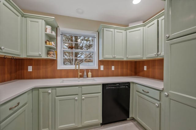 kitchen with black dishwasher, light countertops, a sink, wood walls, and green cabinetry