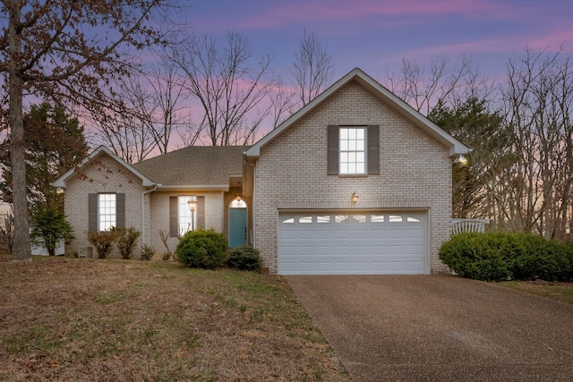 traditional-style house featuring a garage, brick siding, a shingled roof, driveway, and a front lawn