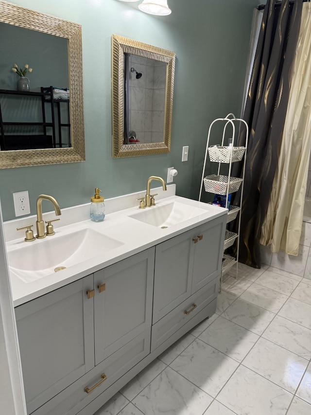 bathroom with double vanity, marble finish floor, tiled shower, and a sink