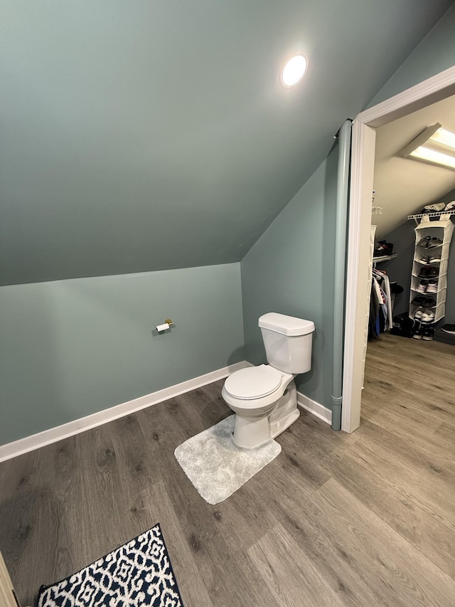 bathroom featuring vaulted ceiling, toilet, baseboards, and wood finished floors