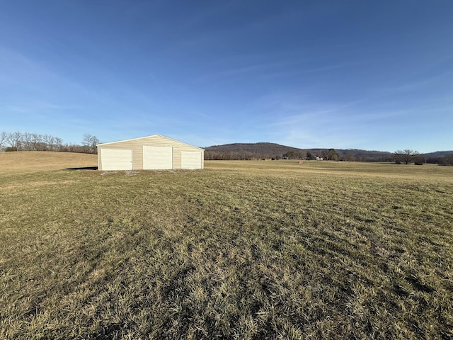 view of yard with a garage, a rural view, and an outdoor structure