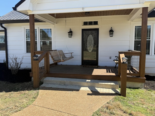 doorway to property featuring a porch and metal roof