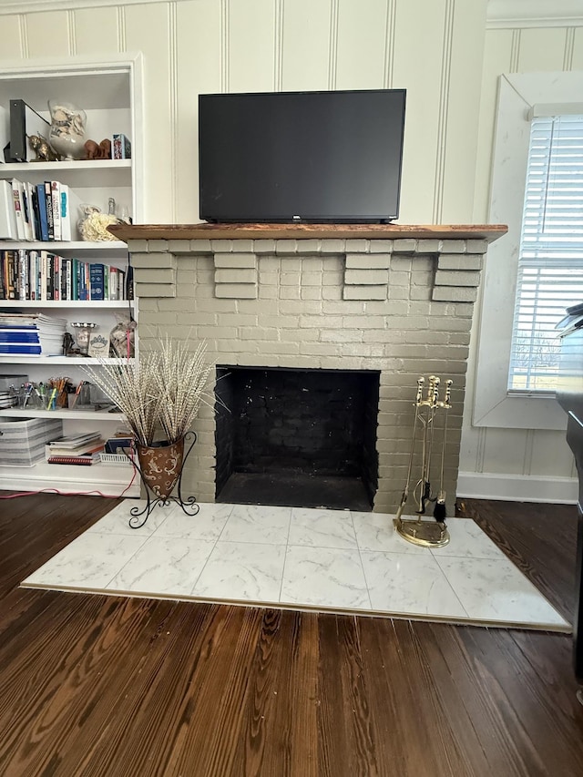 details with a brick fireplace, a decorative wall, and wood finished floors