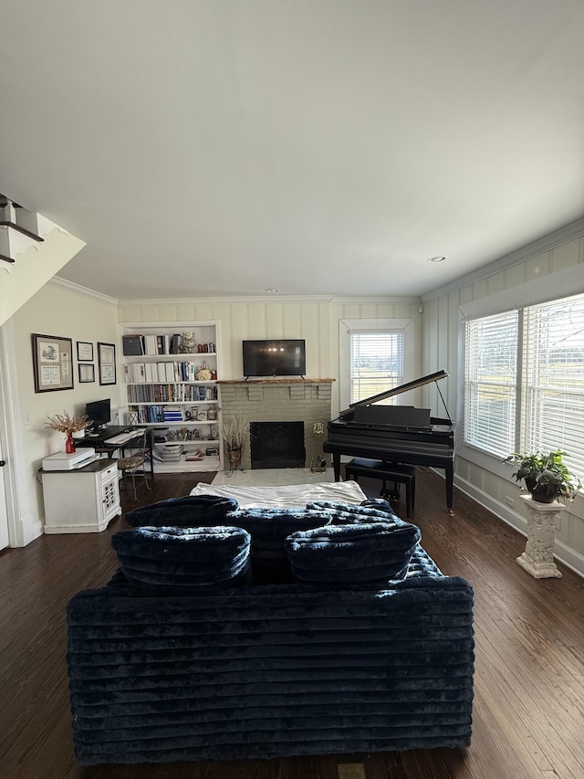 living room with crown molding, a fireplace, baseboards, and wood finished floors