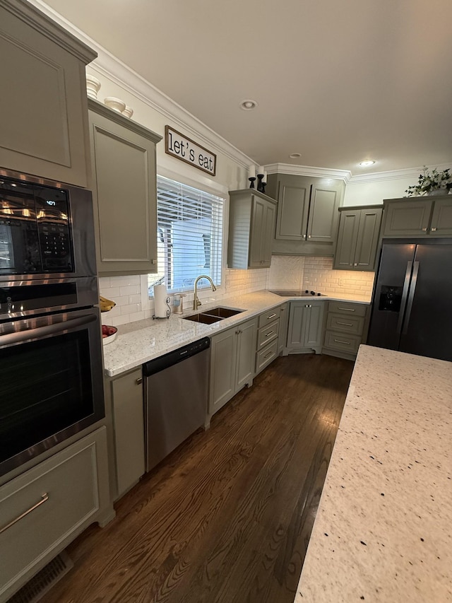 kitchen featuring appliances with stainless steel finishes, decorative backsplash, a sink, and crown molding