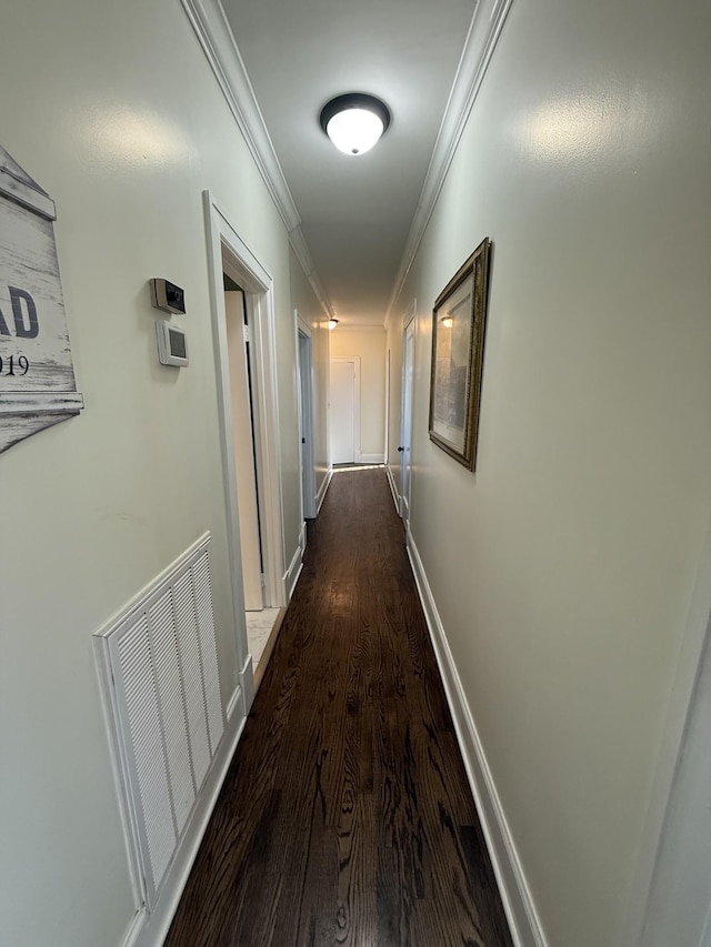 corridor featuring ornamental molding, dark wood finished floors, visible vents, and baseboards