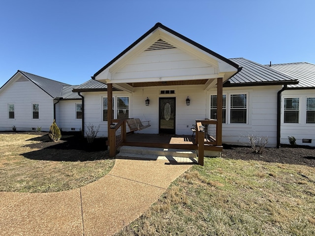 view of front facade featuring covered porch, metal roof, a front lawn, and a standing seam roof