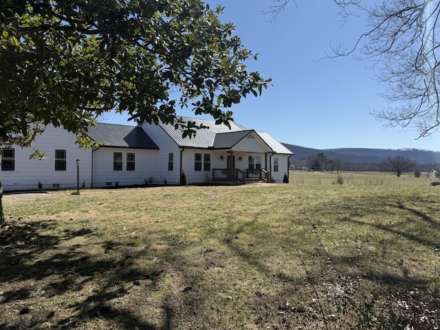 back of property featuring crawl space, metal roof, and a lawn