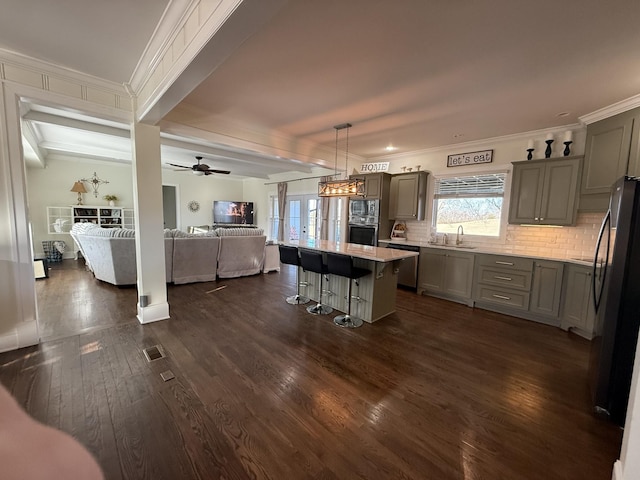 kitchen featuring stainless steel appliances, a breakfast bar area, open floor plan, and gray cabinetry