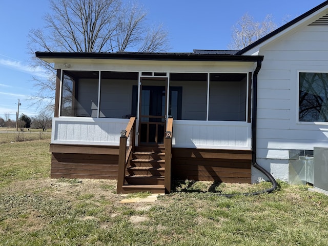 back of house featuring a sunroom, a yard, and metal roof