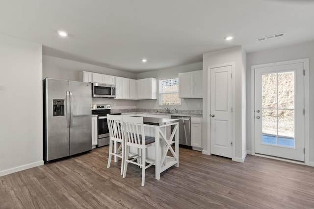 kitchen featuring dark wood-style flooring, stainless steel appliances, light countertops, visible vents, and white cabinets