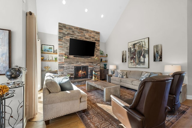 living area with high vaulted ceiling, recessed lighting, a stone fireplace, and wood finished floors