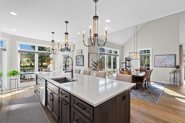 kitchen featuring dark brown cabinetry, a chandelier, a sink, and wood finished floors