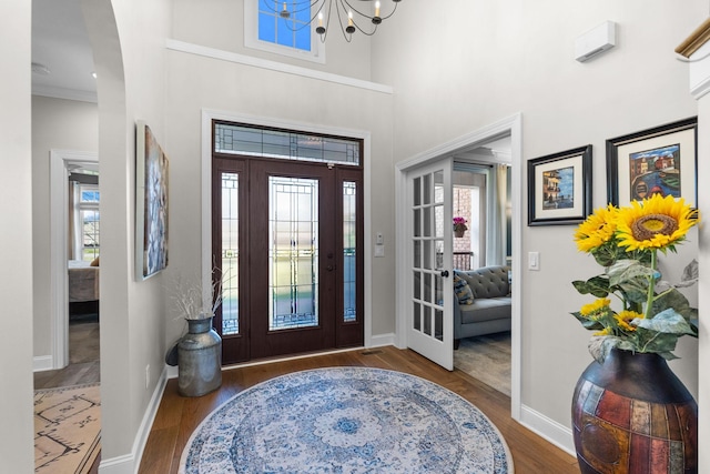 foyer entrance with a towering ceiling, baseboards, and wood finished floors