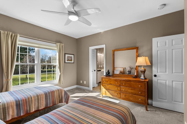 bedroom with light carpet, ensuite bath, ceiling fan, and baseboards