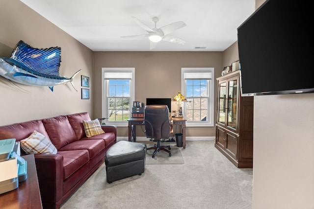 office featuring light colored carpet, ceiling fan, visible vents, and baseboards