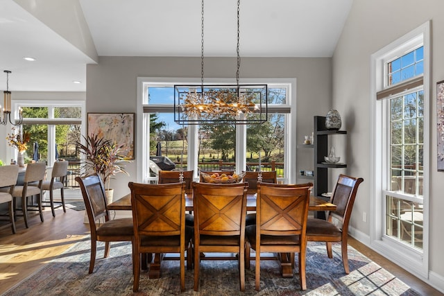 dining area with baseboards, a chandelier, vaulted ceiling, and wood finished floors