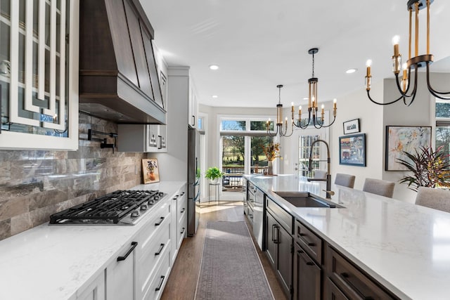 kitchen featuring dark brown cabinetry, dark wood finished floors, an inviting chandelier, stainless steel appliances, and a sink