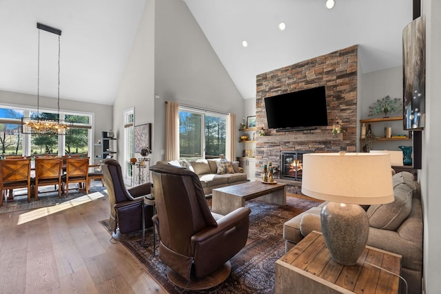 living room featuring plenty of natural light, high vaulted ceiling, wood-type flooring, and a fireplace