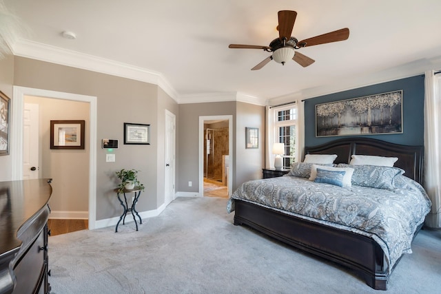 carpeted bedroom featuring a ceiling fan, crown molding, ensuite bath, and baseboards