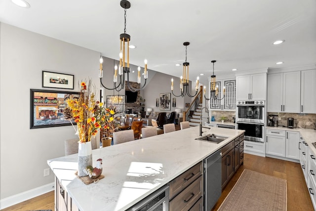 kitchen with tasteful backsplash, white cabinets, wood finished floors, stainless steel appliances, and a sink