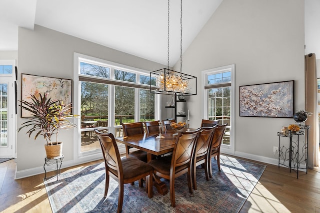 dining space featuring high vaulted ceiling, plenty of natural light, baseboards, and wood finished floors