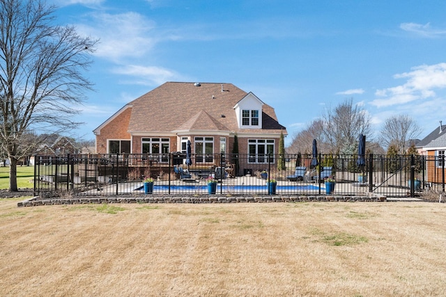 rear view of house with a patio, brick siding, fence, a pool, and a yard