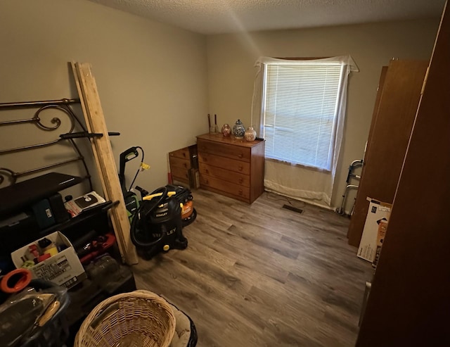 interior space featuring a textured ceiling, wood finished floors, and visible vents