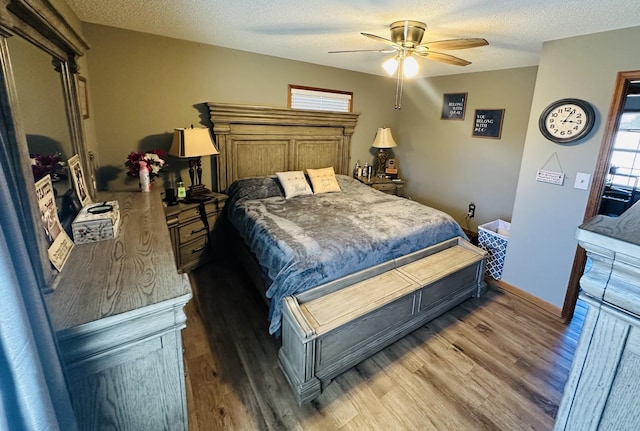 bedroom with a ceiling fan, a textured ceiling, baseboards, and wood finished floors